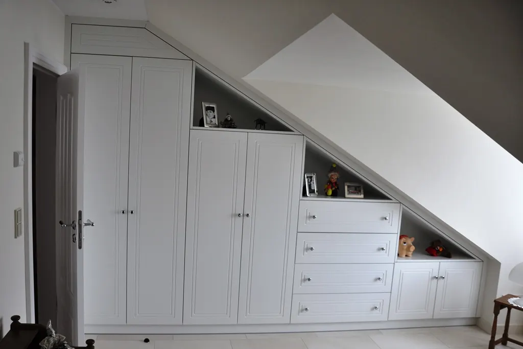 Weißer Einbauschrank, exakt in eine Dachschräge eingepasst