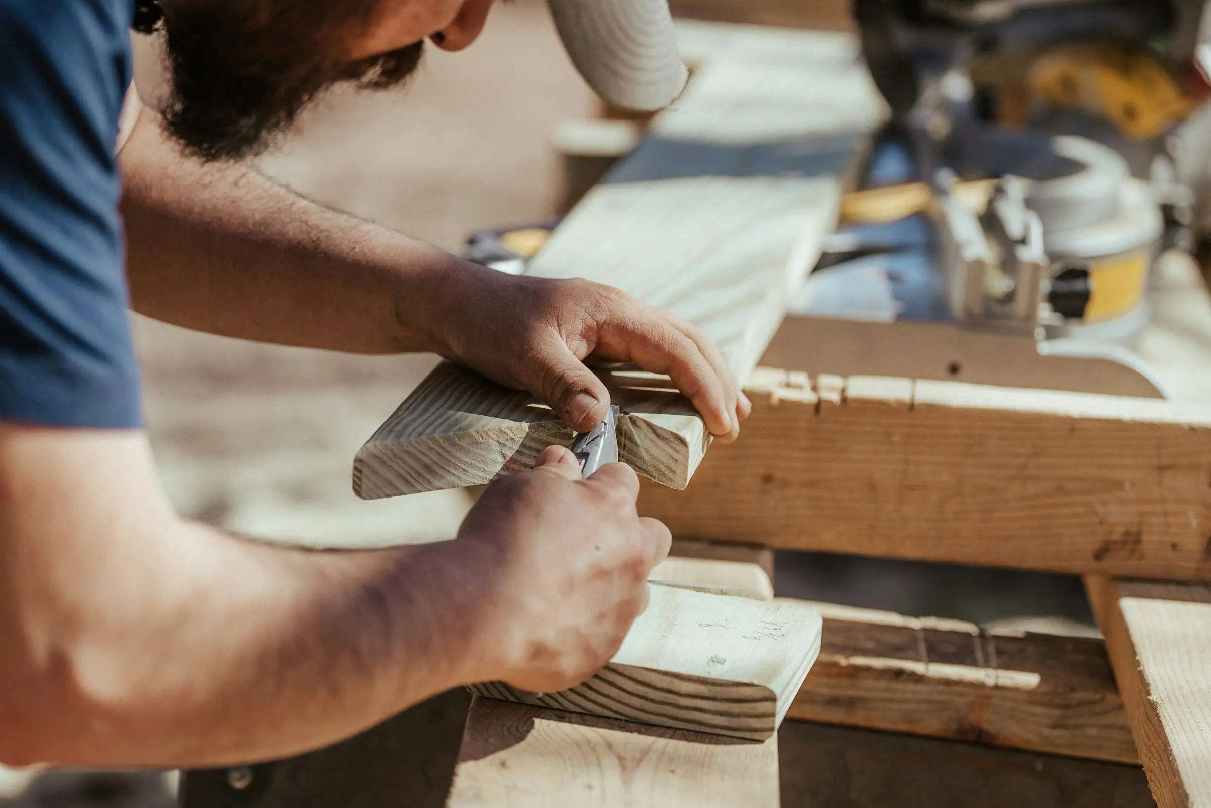 Hände bearbeiten ein Werkstück aus Holz auf der Werkbank